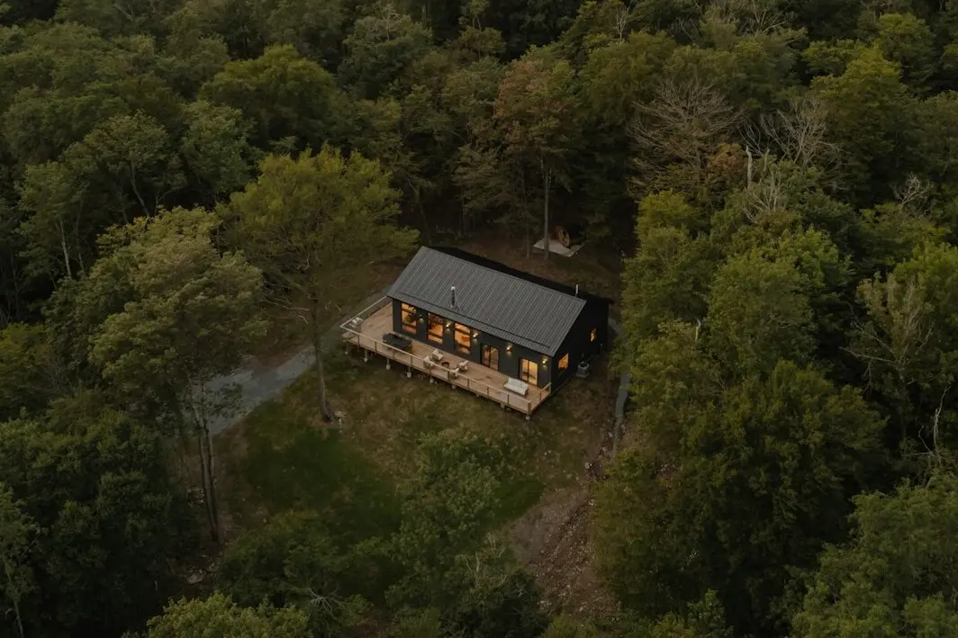 Knus huisje tussen bomen bij zonsondergang